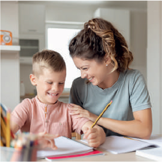 un niño haciendo la tarea con la madre al lado sonriendo